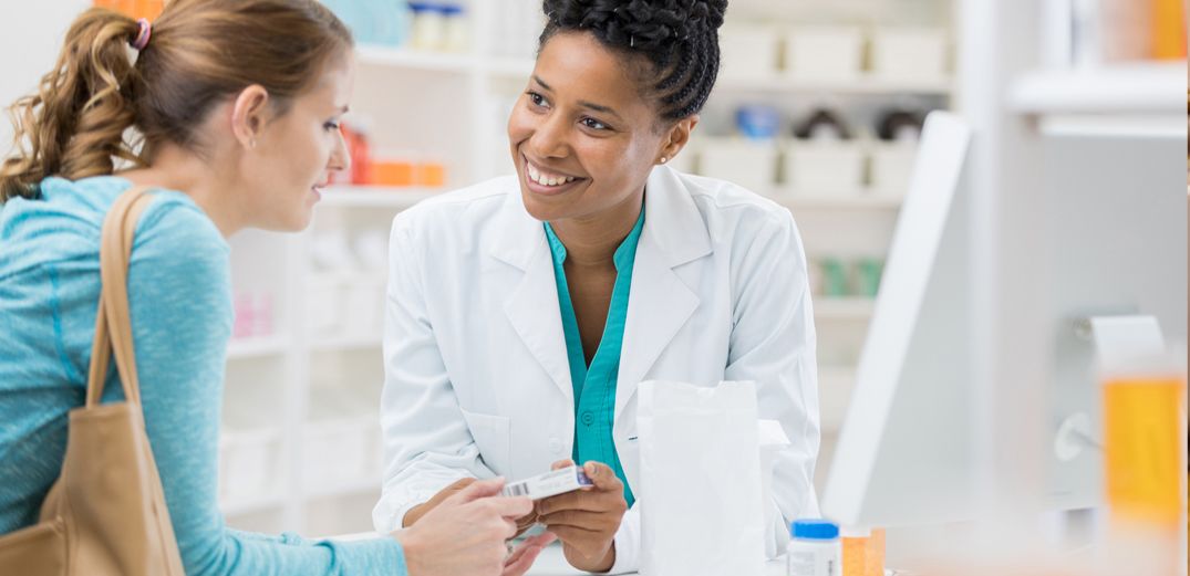 A pharmacist discusses a medication with a customer.