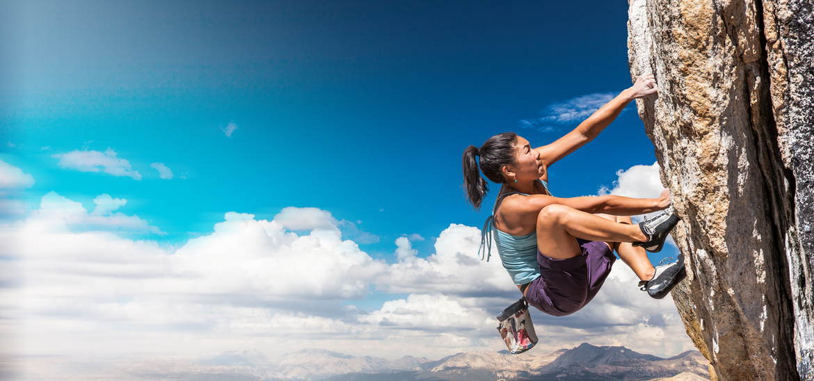 Athlete rock climbing outside with a look of intensity and perseverance.