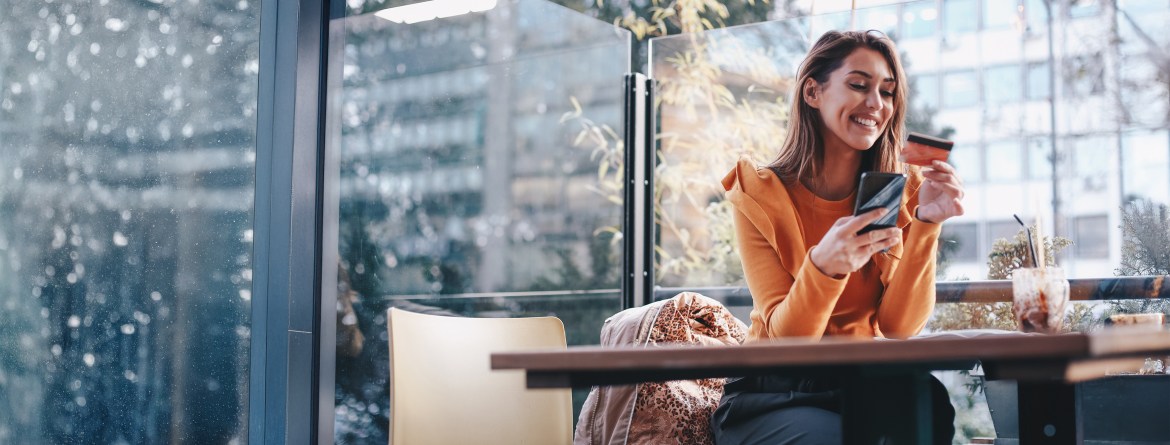 Patelco member happily using her debit Mastercard at a store and enjoying the RoundUp benefits